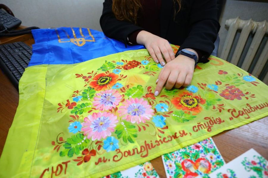 Запоріжанка розписує петриківкою українські прапори для військових
