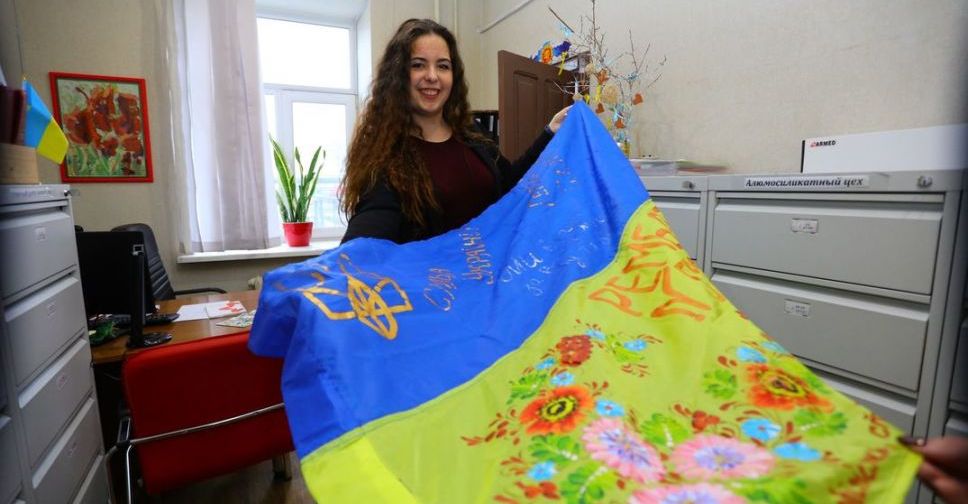 Запоріжанка розписує петриківкою українські прапори для військових